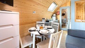 Una cocina compacta con comedor, un refrigerador pequeño y una ventana sobre la mesa.