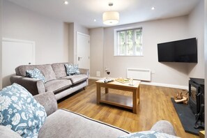 Un salon avec un canapé, une table basse et un téléviseur à écran plat.