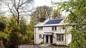 Una casa a due piani con tetto solare, immersa tra gli alberi e con vialetto in ghiaia.