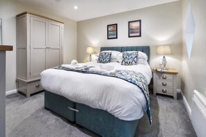 Ein Schlafzimmer mit einem Bett, Nachttischen, einem Kleiderschrank und zwei gerahmten Bildern an der Wand.