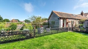 A traditional house with a sloped roof, a stone wall, and a fenced garden. - 1 Bed in Trimingham (oc-h29803) (Trimingham)