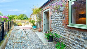A patio with a table and chairs, a hanging flower basket, and a potted plant. - 1 Bed in Trimingham (oc-h29803) (Trimingham)