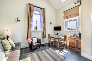 A living room with a sofa, a coffee table, a dining table with chairs, a TV mounted on the wall, and a window with curtains. - 1 Bed in Toynton All Saints (oc-s29840) (Toynton All Saints)