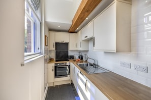 A compact kitchen with white cabinets, a wooden countertop, a built-in oven, and a window providing natural light. - 1 Bed in Toynton All Saints (oc-s29840) (Toynton All Saints)