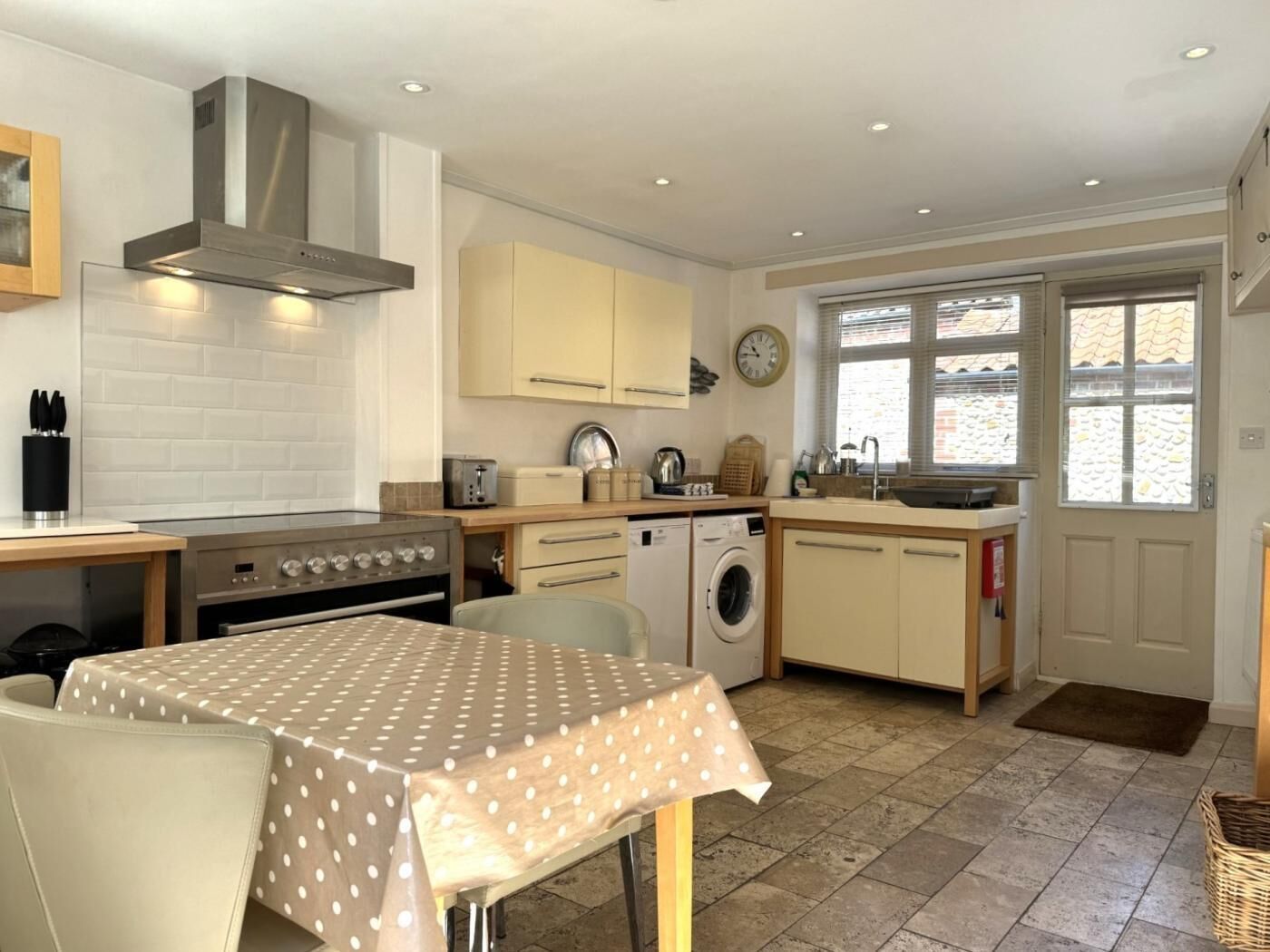 A compact kitchen with a stove, oven, washing machine, and a dining area with a table.