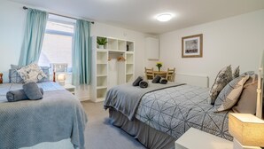 A bedroom with two beds, a wardrobe, a small table with chairs, and a window with curtains. - 2 Bed in Bridlington (oc-o29896) (Bridlington)