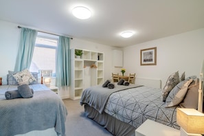 A bedroom with two beds, a wardrobe, a small table with chairs, and a window with curtains. - 2 Bed in Bridlington (oc-o29896) (Bridlington)