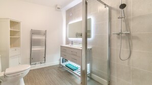 A modern bathroom with a glass shower enclosure, a toilet, a vanity with a mirror, and a towel rack. - 2 Bed in Bridlington (oc-o29896) (Bridlington)