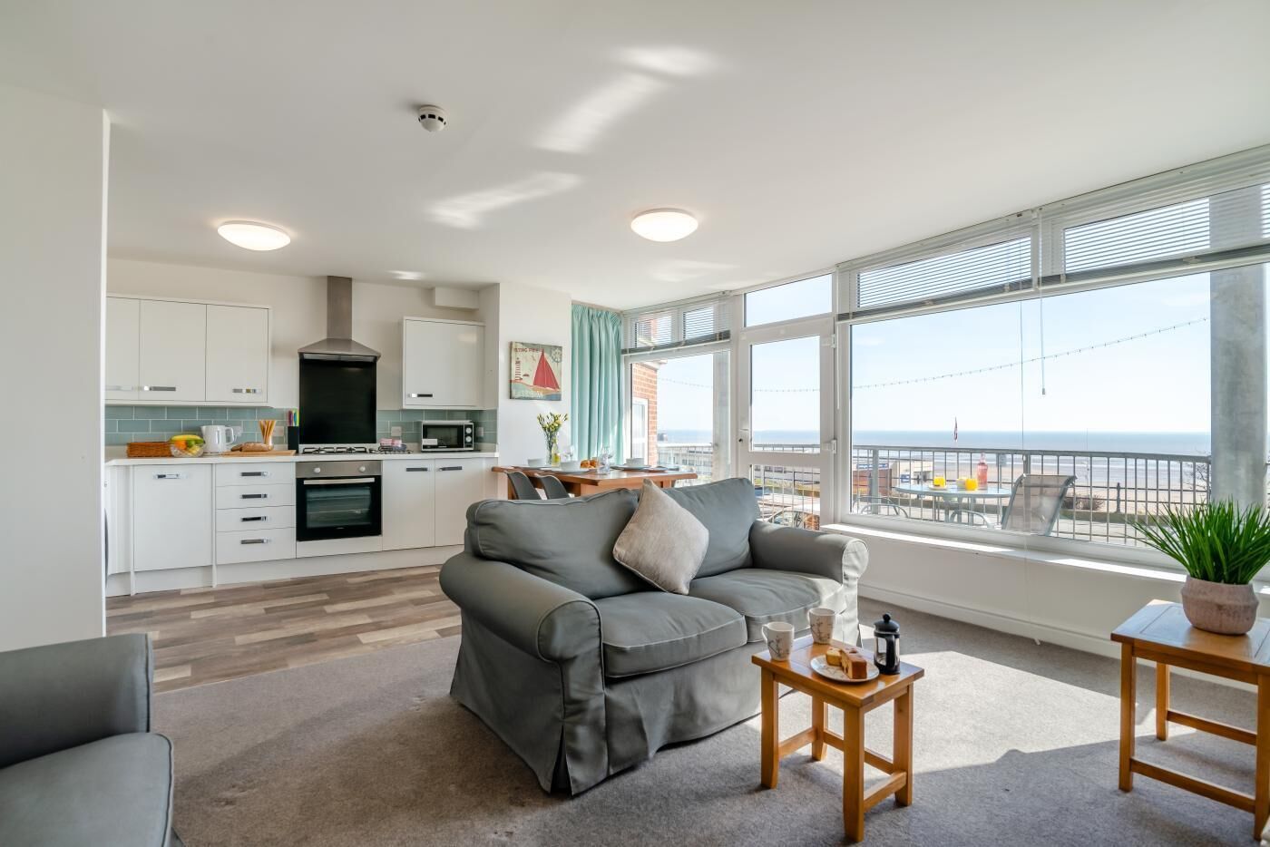 En moderne lejlighed med tekøkken, opholdsstue og balkon med havudsigt.