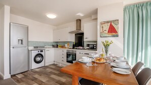 A compact kitchen with a washing machine, oven, and microwave. - 2 Bed in Bridlington (oc-o29896) (Bridlington)