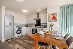 A compact kitchen with a washing machine, oven, and microwave. - 2 Bed in Bridlington (oc-o29896) (Bridlington)