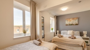 A hotel room with two beds, a large window, a mirror, and a painting on the wall. - 2 Bed in Bridlington (oc-o29897) (Bridlington)