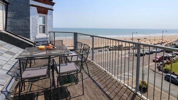 A balcony with a table and chairs overlooking a beach. - 2 Bed in Bridlington (oc-o29897) (Bridlington)