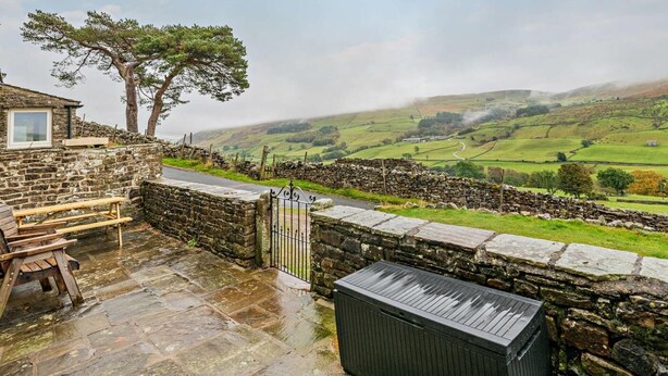 A stone building with a picnic table, a stone wall, and a view of rolling hills. - 3 Bed in Gunnerside (oc-e26693) (Ivelet)