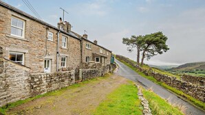 A stone building with a narrow road leading to a stone wall and a tree. - 3 Bed in Gunnerside (oc-e26693) (Ivelet)