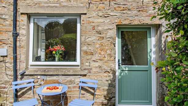 Un edificio in pietra con una finestra adornata di fiori e una porta verde.