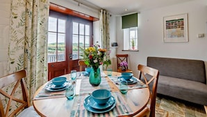 A dining area with a round table set for four, surrounded by chairs. A vase with flowers is placed in the center. - 2 Bed in Loveston (oc-l29792) (Reynalton)