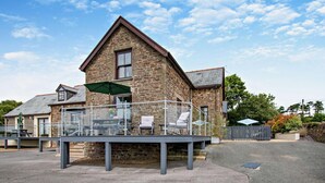 A stone building with a balcony, outdoor seating, and a clear sky. - 2 Bed in Loveston (oc-l29792) (Reynalton)