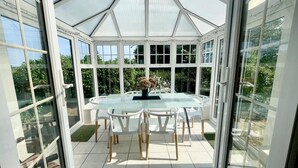 A conservatory with a glass table and chairs, surrounded by large windows. - 3 Bed in Docking (oc-g29874) (Docking)