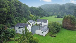 A white building with a sloped roof surrounded by lush greenery and hills in the background. - 3 Bed in Two Waters Foot (oc-l29857) (Broadoak)