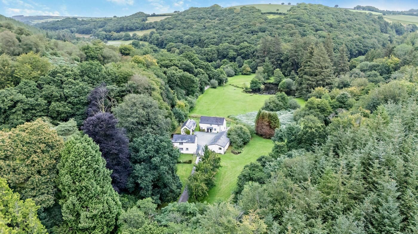 A large house surrounded by lush greenery and hills.