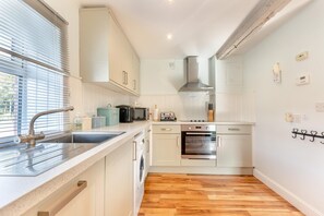 A compact kitchen with a sink, stove, oven, and microwave. - 2 Bed in Langtree (oc-o29910) (Langtree)