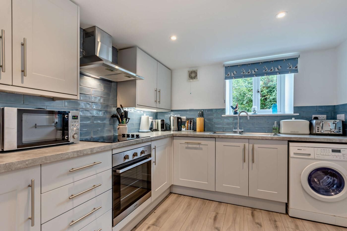 A modern kitchen with a built-in oven, microwave, and washing machine.