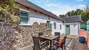 Una casa in pietra con un patio, un tavolo e sedie, e una porta.