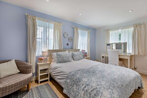 A bedroom with a bed, bedside tables, a desk, and a chair.