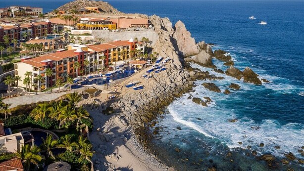 Un hotel costero con varias edificaciones, un litoral rocoso y vista al océano.