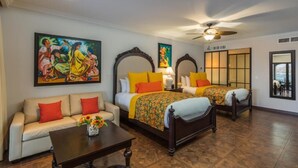 Habitación de hotel con dos camas, un sofá, una mesa de centro y obras de arte en las paredes.