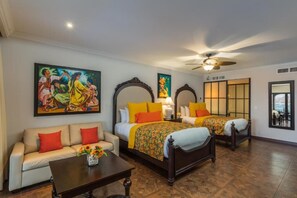 Ein Hotelzimmer mit zwei Betten, einem Sofa, einem Couchtisch und Bildern an den Wänden.