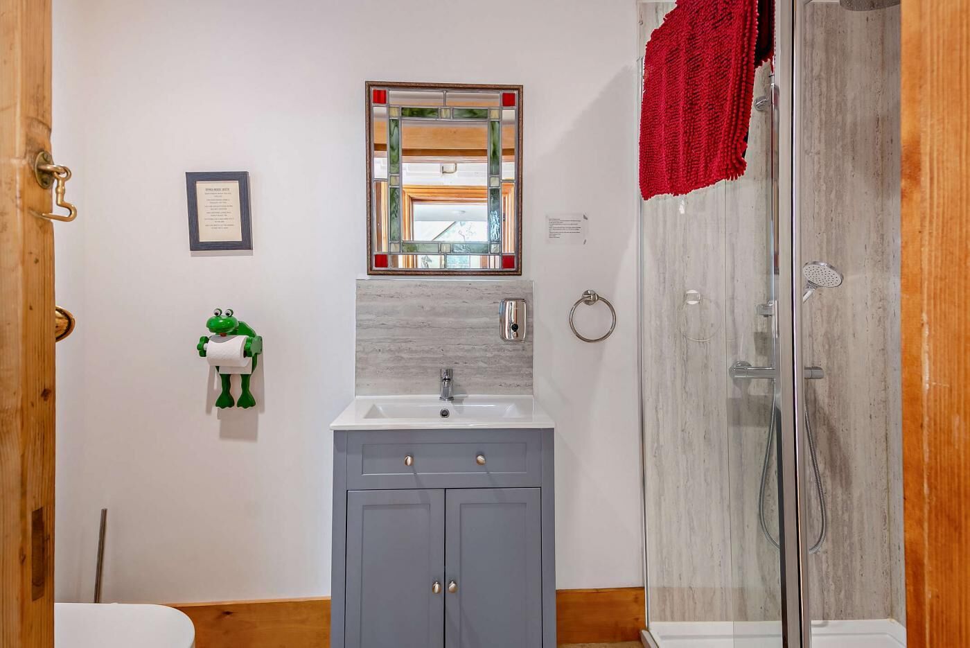 A bathroom with a sink, mirror, and shower.
