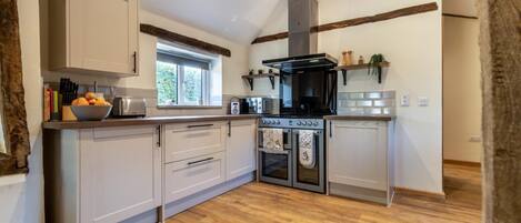 A modern kitchen with wooden flooring, a built-in oven, and a window providing natural light.