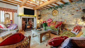 Una habitación acogedora con pared de piedra, chimenea, muebles de mimbre y techo de madera.