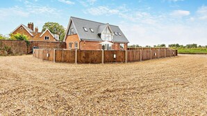 A stable with a wooden fence, a gravel ground, and a brick building with a sloped roof. - 4 Bed in Cawston (oc-p29906) (Cawston)