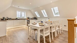 A modern kitchen with white cabinets, a dining table with chairs, and skylights. - 4 Bed in Cawston (oc-p29906) (Cawston)