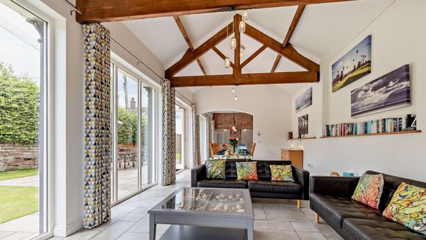 Un salon spacieux avec un haut plafond, de grandes fenêtres, une cheminée et un coin repas.