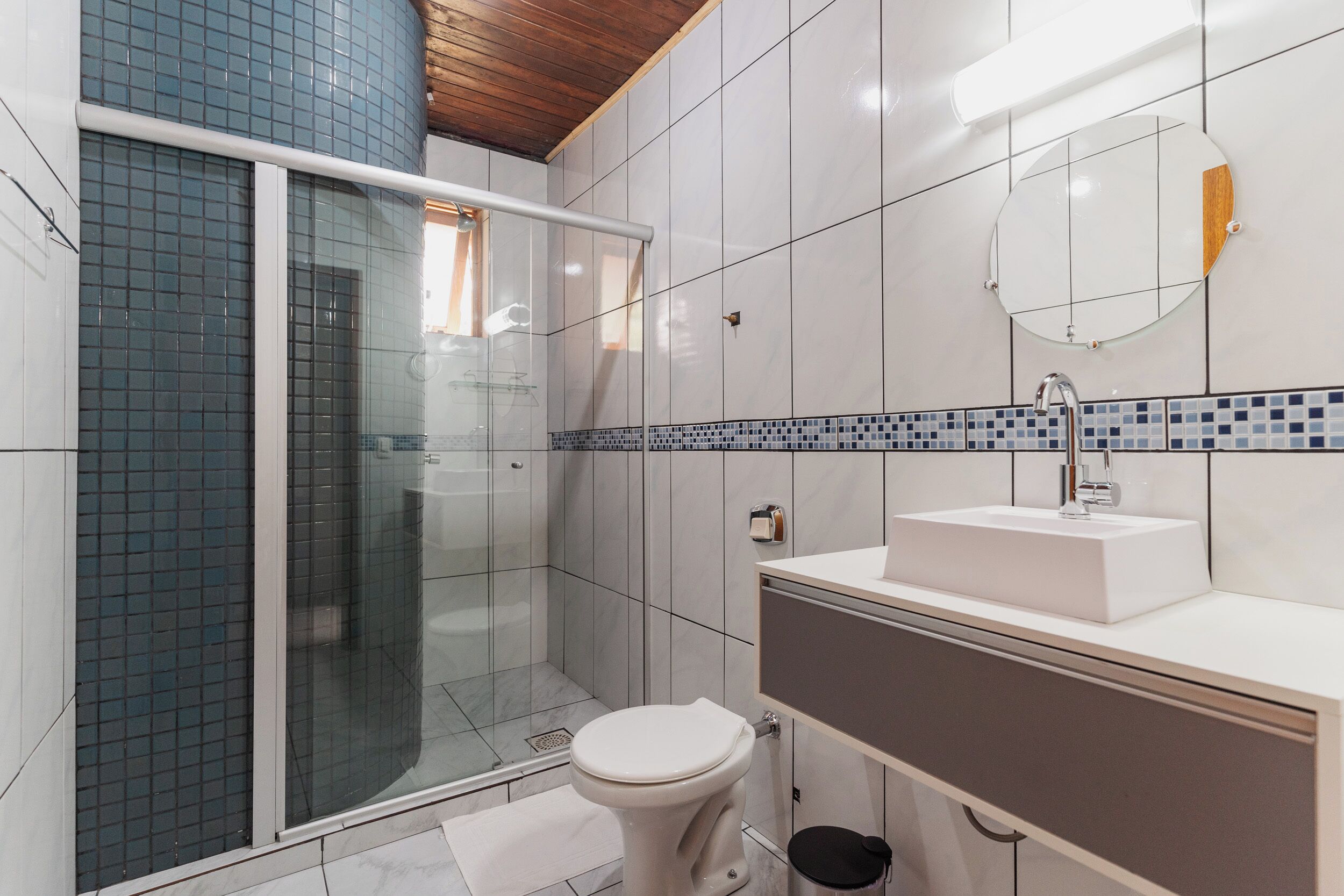 A modern bathroom with a glass shower enclosure, a white toilet, and a sink with a mirror above it.