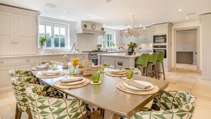 Una cocina moderna con una isla grande, armarios blancos y un comedor con sillas de diseño verde.