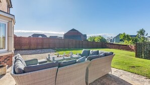 A patio area with a wicker sofa, a small table, and a glass window. - 4 Bed in Beadnell (oc-s29958) (Beadnell)