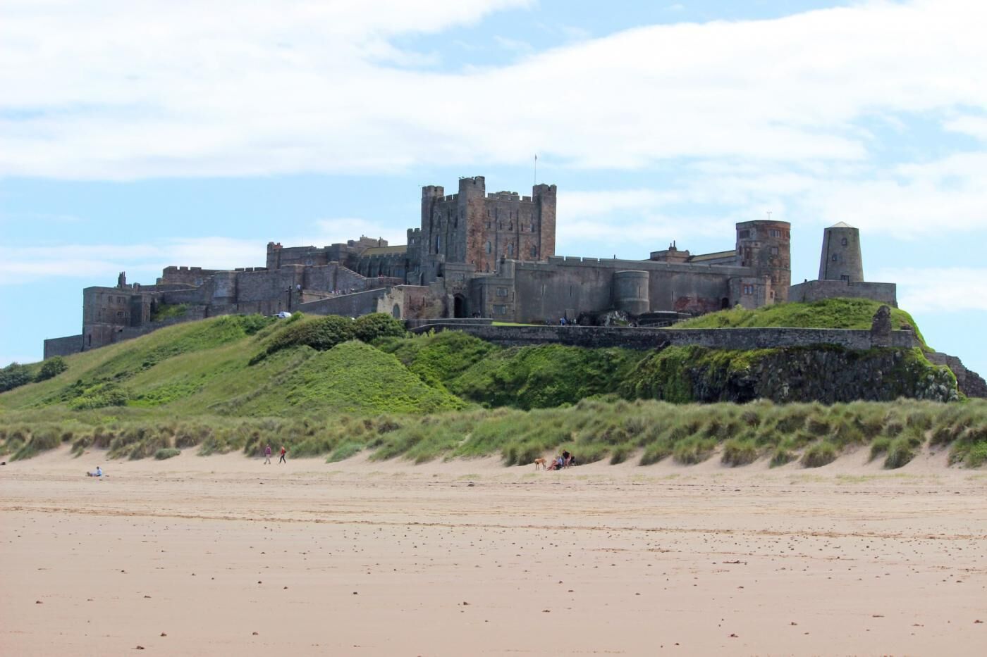 Um castelo histórico numa colina com vista para uma praia.