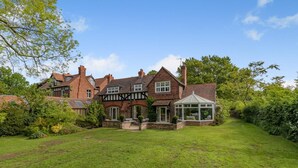A large, traditional house with multiple chimneys, a conservatory, and a well-maintained lawn. - 3 Bed in Thelwall (oc-c29954) (Warrington)