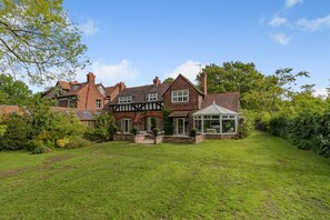 A large, traditional house with multiple chimneys, a conservatory, and a well-maintained lawn. - 3 Bed in Thelwall (oc-c29954) (Warrington)
