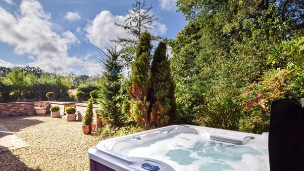 A hot tub in a garden with potted plants and trees. - 3 Bed in Thelwall (oc-c29954) (Warrington)