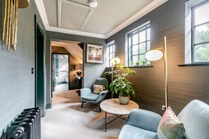 Un salon moderne avec une table basse ronde, deux fauteuils, un lampadaire et une plante en pot.