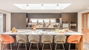 A modern kitchen with a large island, dark cabinetry, and a skylight above the island. - 4 Bed in Helmsley (oc-l29736) (Helmsley)