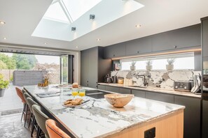 Una cucina moderna con una grande isola, un lucernario e vista sull'esterno.