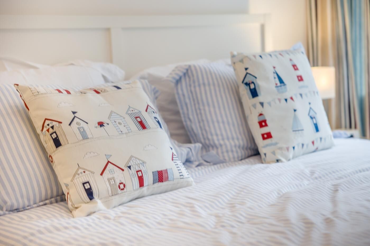 Ein Bett mit gestreifter Bettwäsche und dekorativen Kissen mit Meeresmotiven.