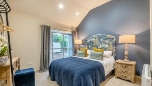 A bedroom with a large bed, bedside lamps, a dresser, and a view through a window.